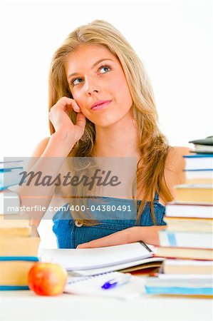 Young girl sitting at table with books and dreamy looking in corner