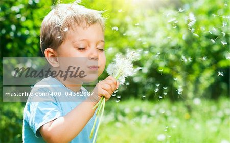 Cute 2 years old boy with dandelion outdoors at sunny summer day