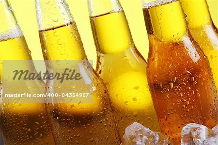Bottles of cold and fresh beer with ice over yellow background