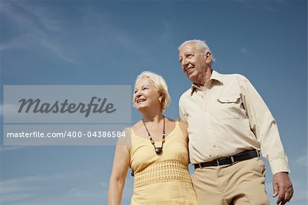 senior caucasian couple walking on sunny day and hugging. Horizontal shape, low angle view, copy space