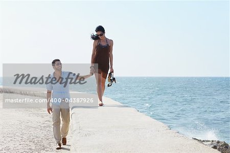 happy married couple walking hands in hands along the caribbean sea. Horizontal shape, full length, copy space