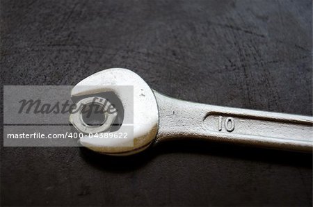 Nut and spanner on metal workbench background