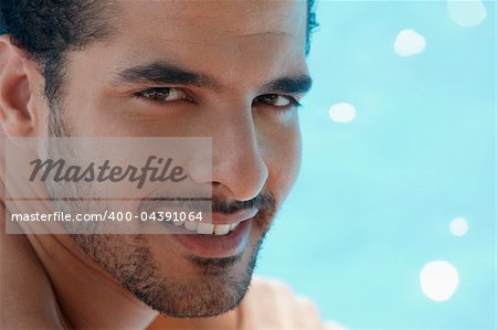 Handsome happy young hispanic man smiling and relaxing near hotel pool. Horizontal shape, headshot, copy space