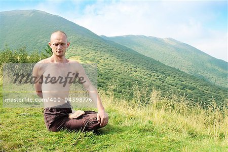 Young man is occupied yogi in the foot of the mountains