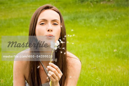 Girl with dandelion on green field