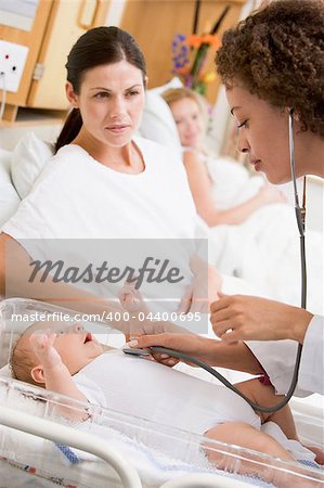 Doctor checking baby's heartbeat with new mother watching