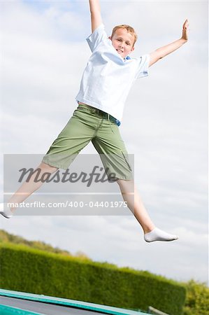 Young boy jumping on trampoline smiling