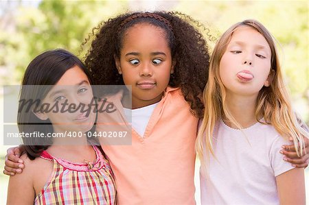 Three young girl friends outdoors making funny faces