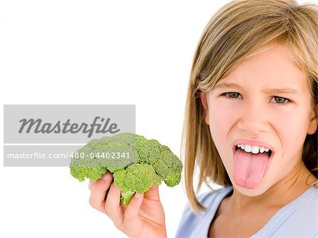 Young girl holding broccoli and sticking tongue out