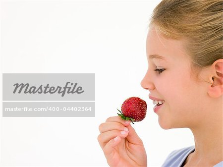 Young girl eating strawberry smiling