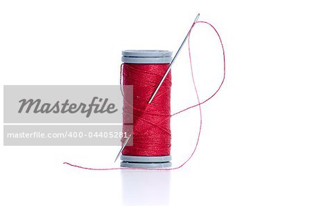 Red thread bobbin and needle on white background.