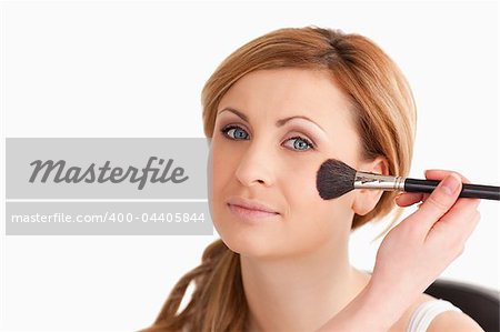 Make-up artist applying make up to an attractive blond-haired woman in a studio