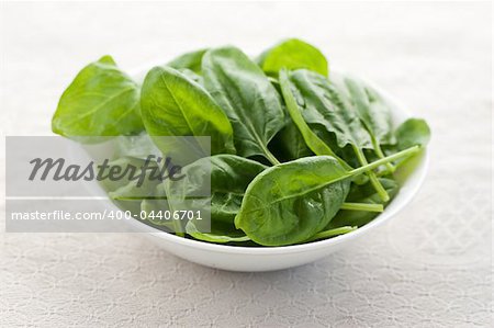 Fresh spinach in a bowl on white background