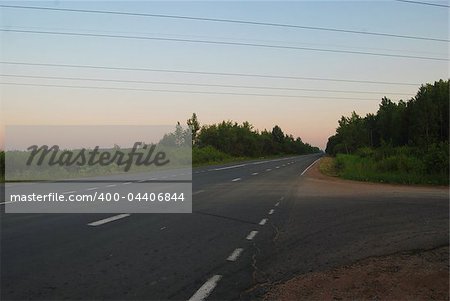 Landscape with asphalted road and trees over still evening sky