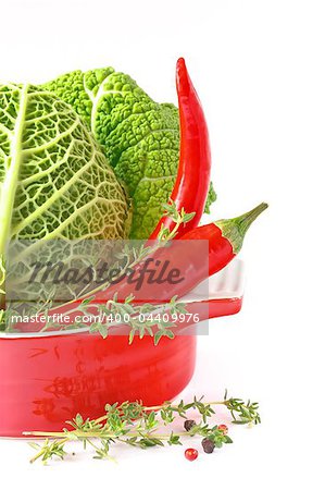 Savoy cabbage and ?hili in a red ?eramic saucepan.