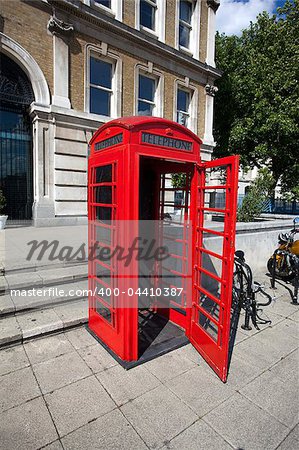 Old red phone booth with open door in London