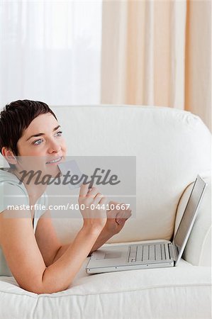 Portrait of a pensive woman buying online in her living room