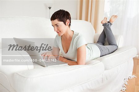 Happy short-haired woman using a laptop in her living room