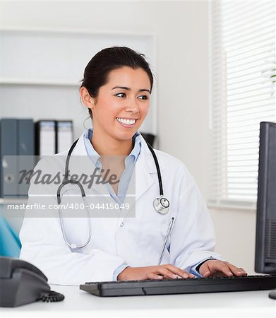 Beautiful woman doctor typing on a keyboard in her office