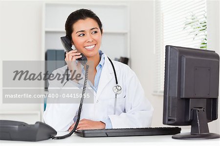 Attractive woman doctor on the phone while sitting in her office