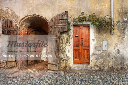 Wooden door and gate entrance to garage in old brick house in town of Saluzzo, northern Italy.