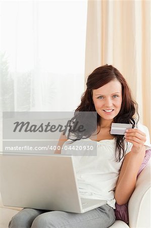 Woman doing online shopping looking at the camera in her livingroom