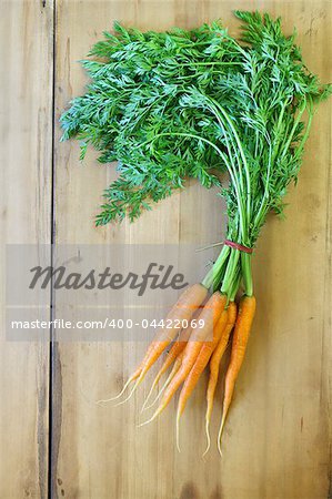 Fresh organic carrots with leaves on a wooden background
