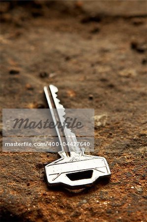 A bright key with shadow over the stone background. Shallow DOF