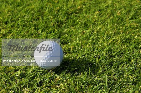 Single golf ball lying on green grass on fairway.