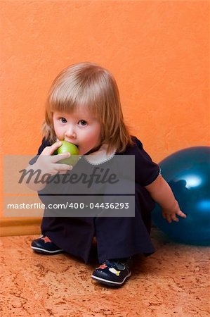 cute little girl with green apple sitting on the floor