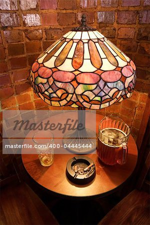 High angle still life of table with beer glass, pitcher, and cigarette ashtray in nightclub.