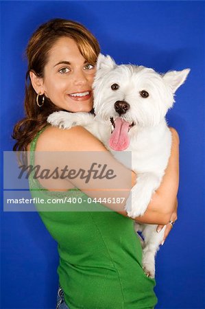 Caucasian prime adult female holding white terrier dog.