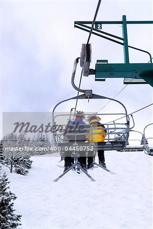 Skiers wearing funny hats on a chairlift in snowy mountains