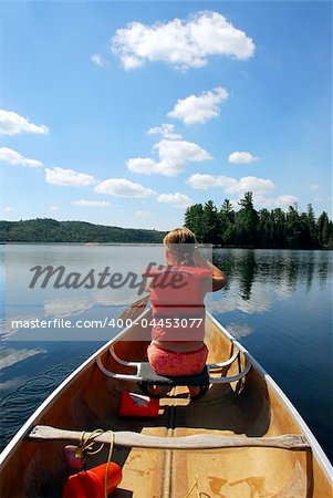 Young girl in canoe paddling on a scenic lake