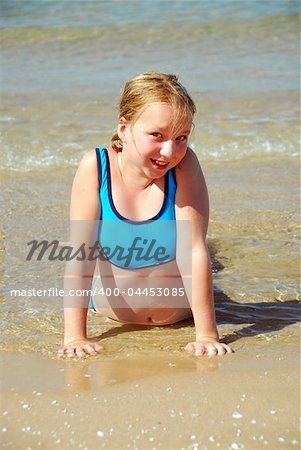 Young girl lying on a beach in shallow water