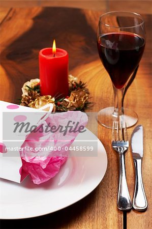 Table setting with a pink polka-dot gift bag on white plate and candle in the background