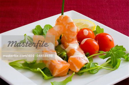 fresh salmon slice on white platter with salad and prawns served with yogurt cream