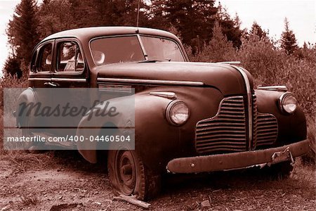 sepia toned abandoned antique automobile parked in field