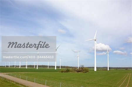 Windmill on a flat landsacpe capturing engergy against a blue sky
