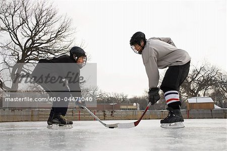 Two ice hockey player boys in uniform facing off on ice.