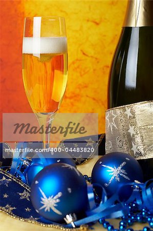 Christmas decoration with champagne bottle and full glass over colour background. Shallow DOF
