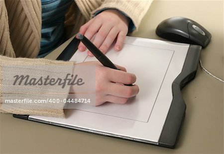 Female hands drawing with the stylus of a computer graphics tablet.