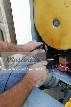 A closeup of an air conditioning tech as he tests the voltage on a heat recovery unit.