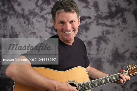 A handsome, middle aged guitarist with a big, toothy smile.