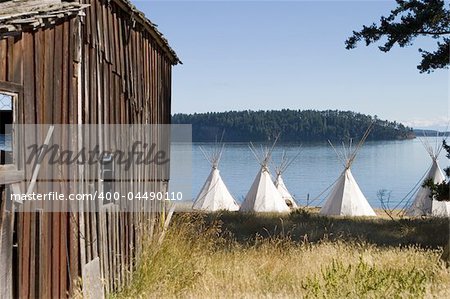 A group of teepees located near an old barn. This scene represents the mix of the American West with the traditional Native American cultures.