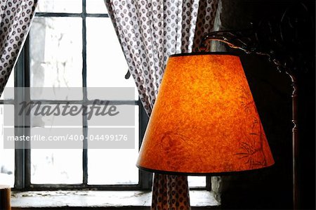 Warm colored lamp near a window looking out onto a winter scenic