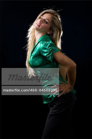 beautiful young woman with blond hair wearing shiny green satin blouse posing on black background