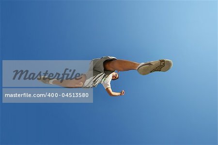 young man jumping over camera over blue sky