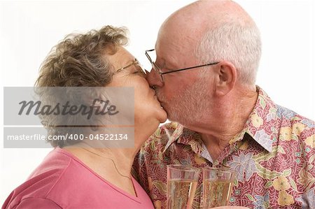 Happy Senior Couple kissing while holding Champagne glasses.
