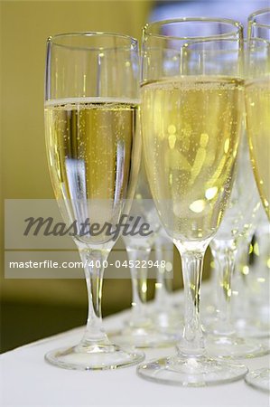 Some glasses with a white sparkling wine stand on the brink of a table